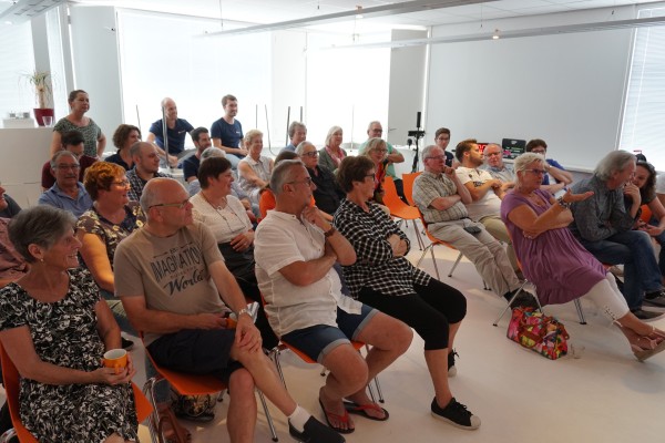 Het aanwezige publiek luistert aandachtig.